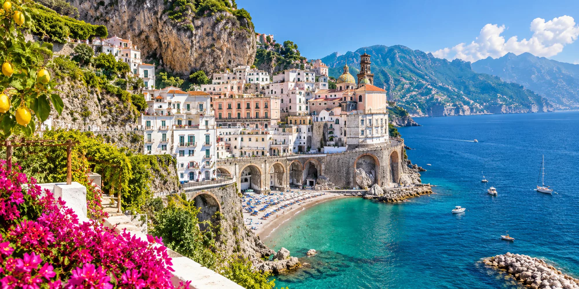 White and pastel houses stacked down a cliff to a small beach on the Amalfi Coast