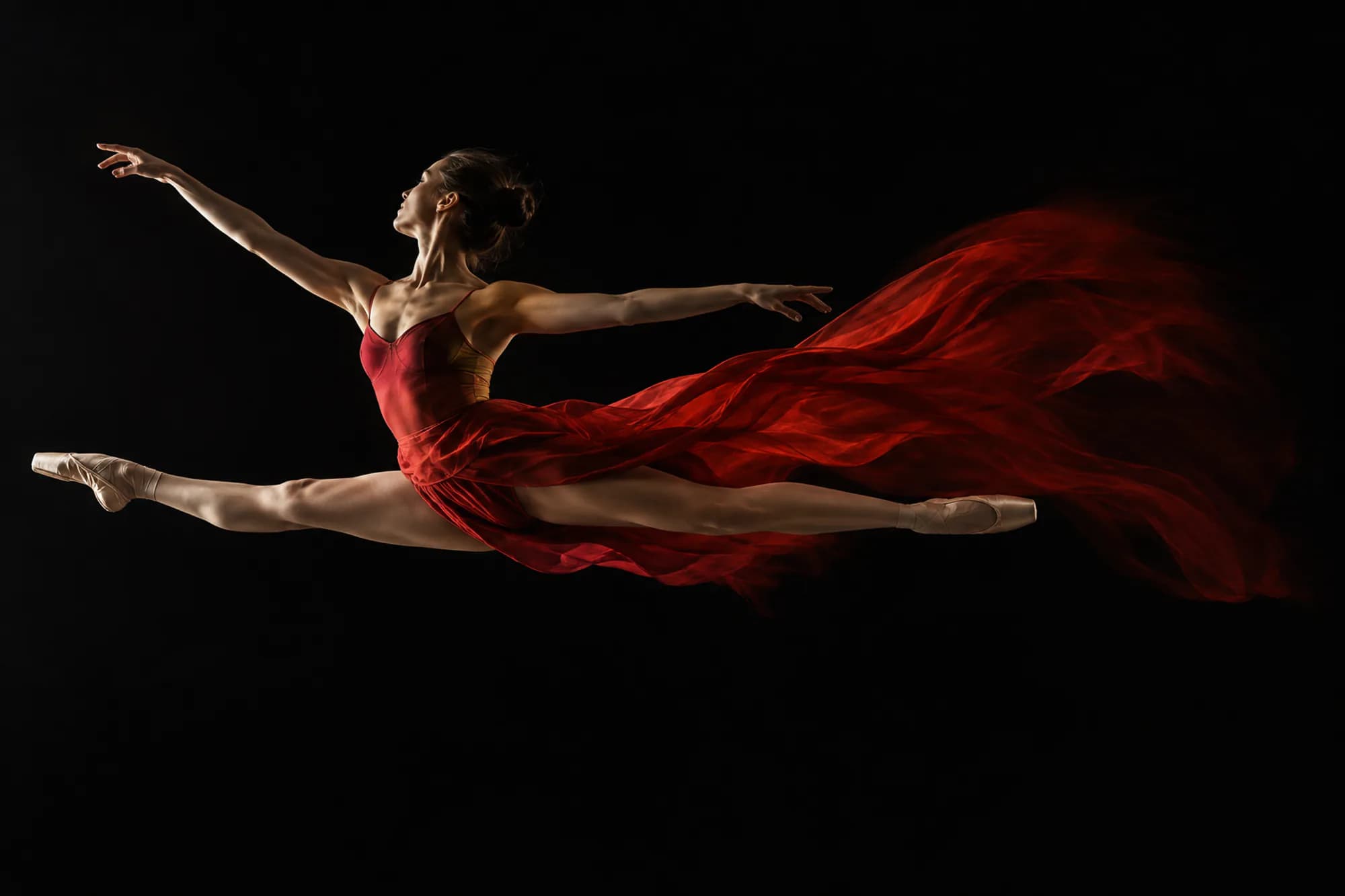 A ballet dancer mid-leap with a vermilion silk skirt streaming behind her